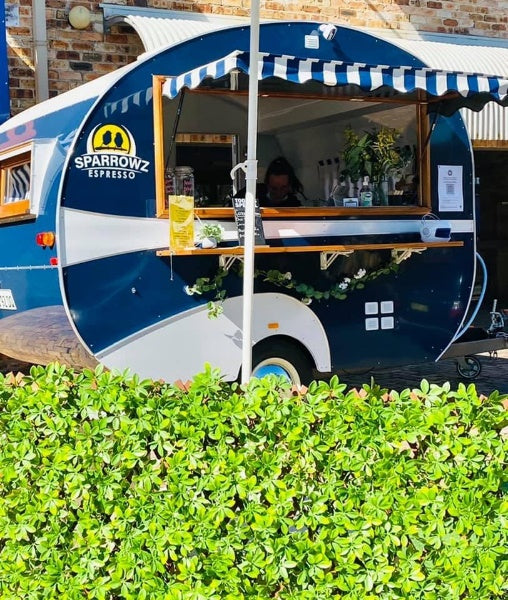 Blue and white vintage-style mobile coffee trailer featuring custom vinyl business logo 'SPARROW ESPRESSO' with yellow circular branding, showcasing durable outdoor signage by AJ's Infinity Design perfect for food trucks and mobile businesses, professional quality vehicle graphics creating eye-catching brand identification for small business entrepreneurs